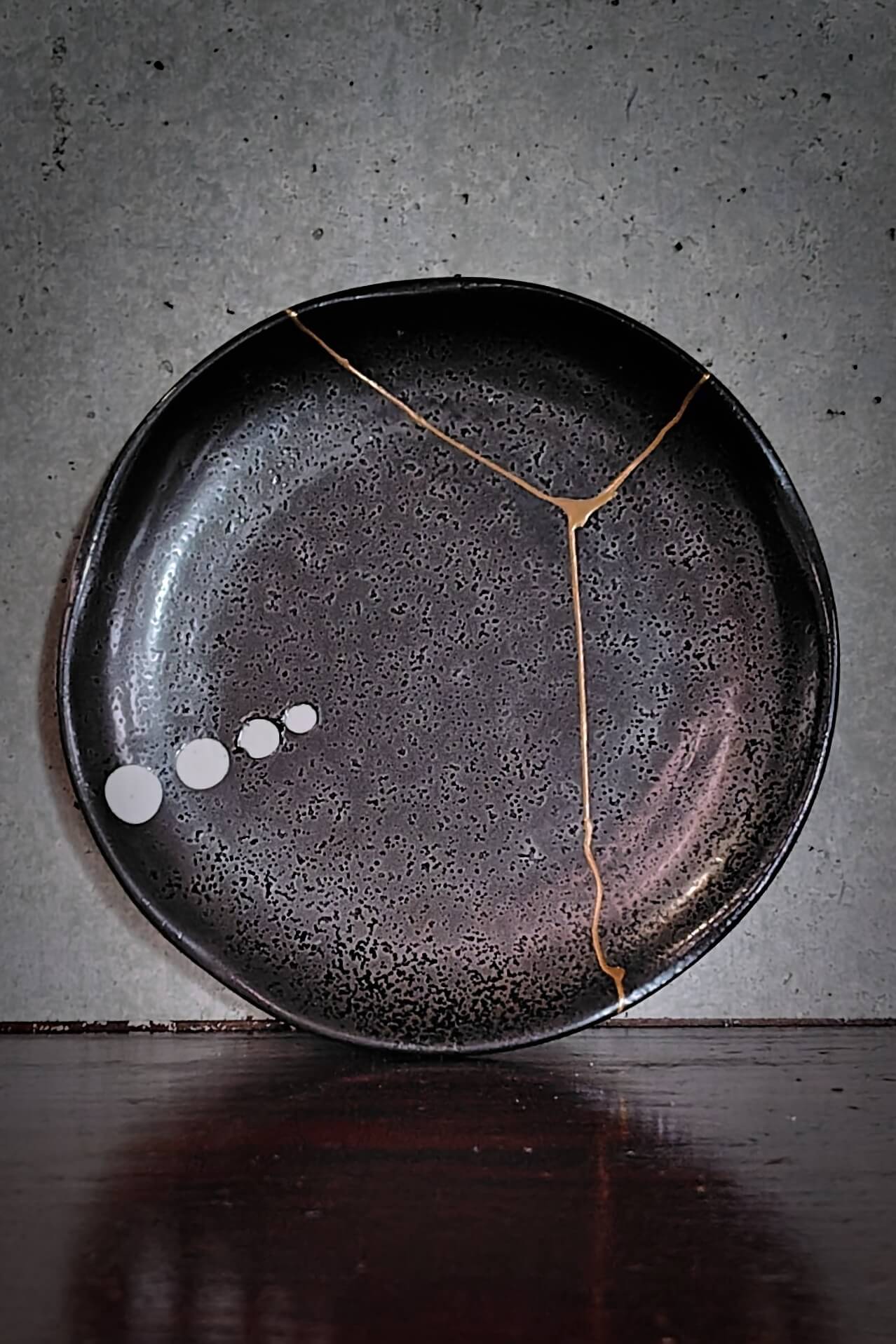 Black ceramic plate repaired with gold kintsugi lines in Kyoto Kintsugi Studio by Matsuda